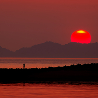 中島に落ちる夕日と釣り人