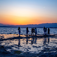 名残惜しい夕日の光と水面に映る人々のシルエット。