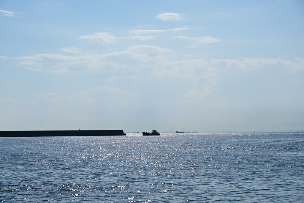 快晴の海と防波堤と船。