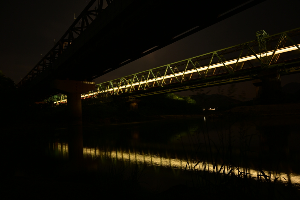 夜の鉄橋と電車と川。