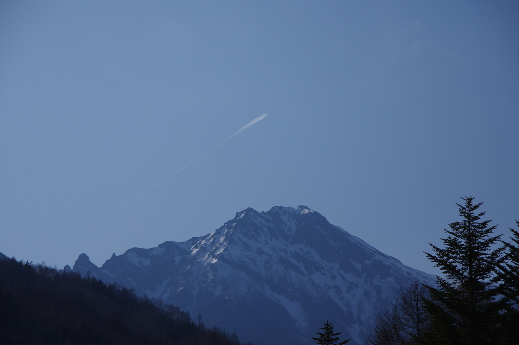 初春の雪山と飛行機雲