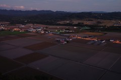 田畑と車灯の夕暮れ