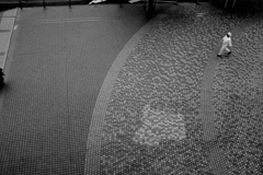 広場を横切る白い帽子の男