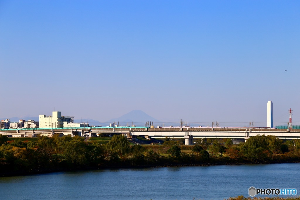 うっすらと見える富士山を背景に新幹線が通過します。