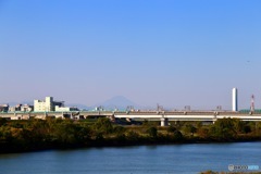 うっすらと見える富士山を背景に新幹線が通過します。