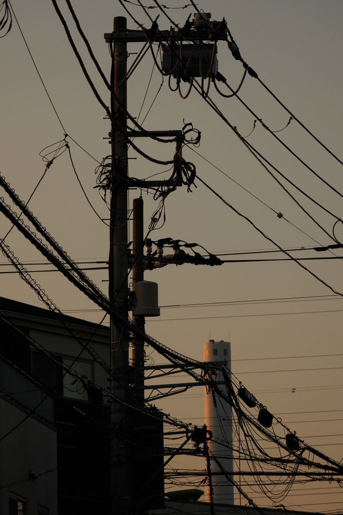 煙突と煩雑なケーブル類が見える夕景
