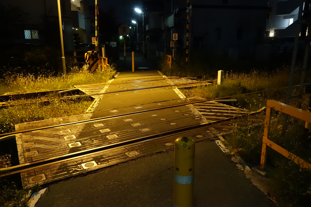 夜の灯りに浮かび上がる小さな踏切