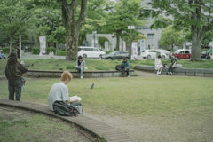 広場で本を読む青年