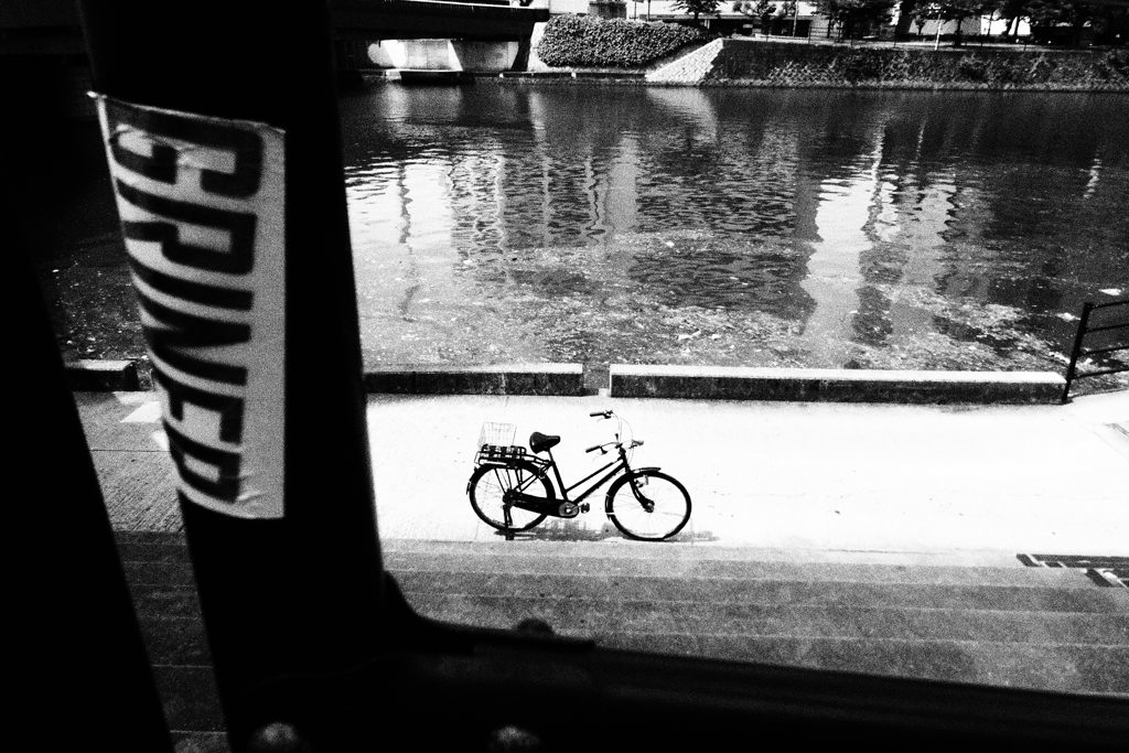 自転車と川と柱に貼られたステッカー