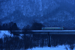 夕暮れの夕張川を往く単行列車