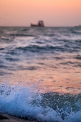 船と夕陽と波しぶき