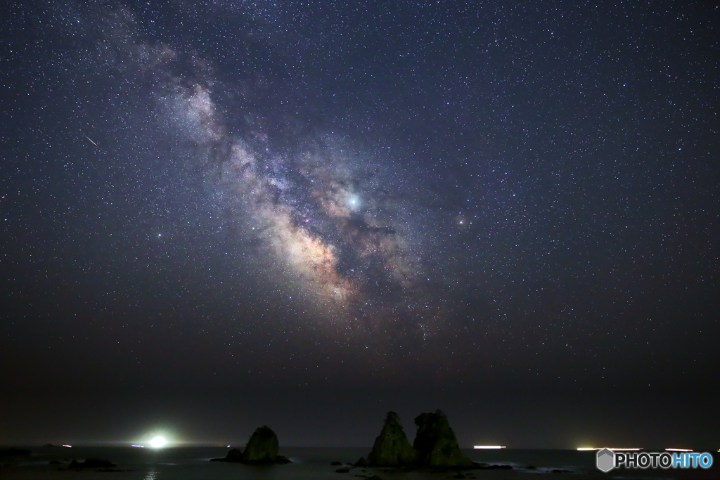 岩礁から立ち登る天の川と流星