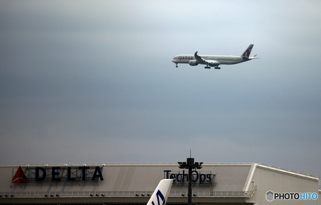 雲と成田空港の風景・ホヌの尾翼とQATAR A350