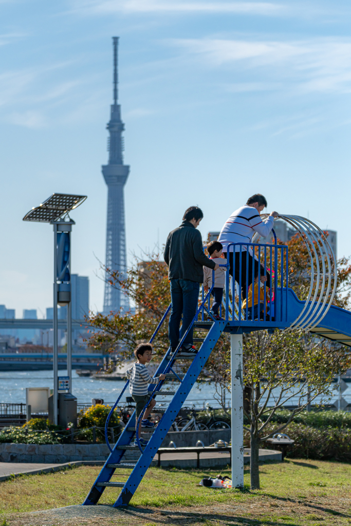 遊具で遊ぶ親子とスカイツリー