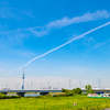 広大な青空と飛行機雲と小さなスカイツリー