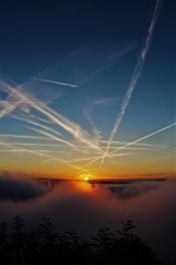 雲海に上る朝日と飛行機雲