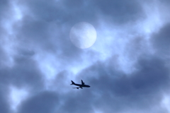 雲に陰る太陽と、成田から飛び立った旅客機