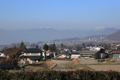 遠く北アルプスを望む村
