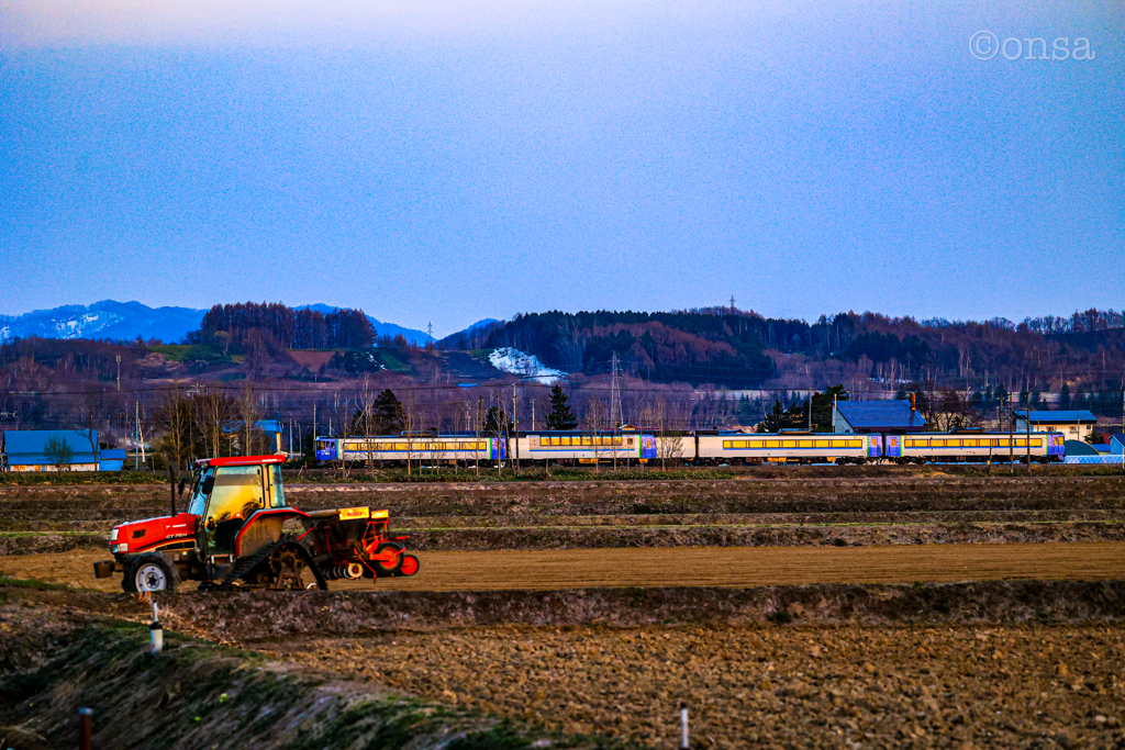 夕焼け映る田起こしの春