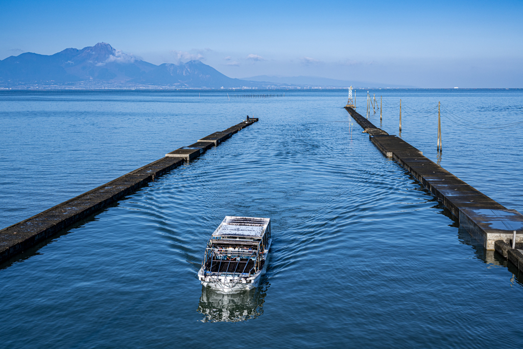 堤防に帰還する海苔漁船