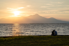 幸せいっぱいのカップルと夕日に染まる雲仙普賢岳