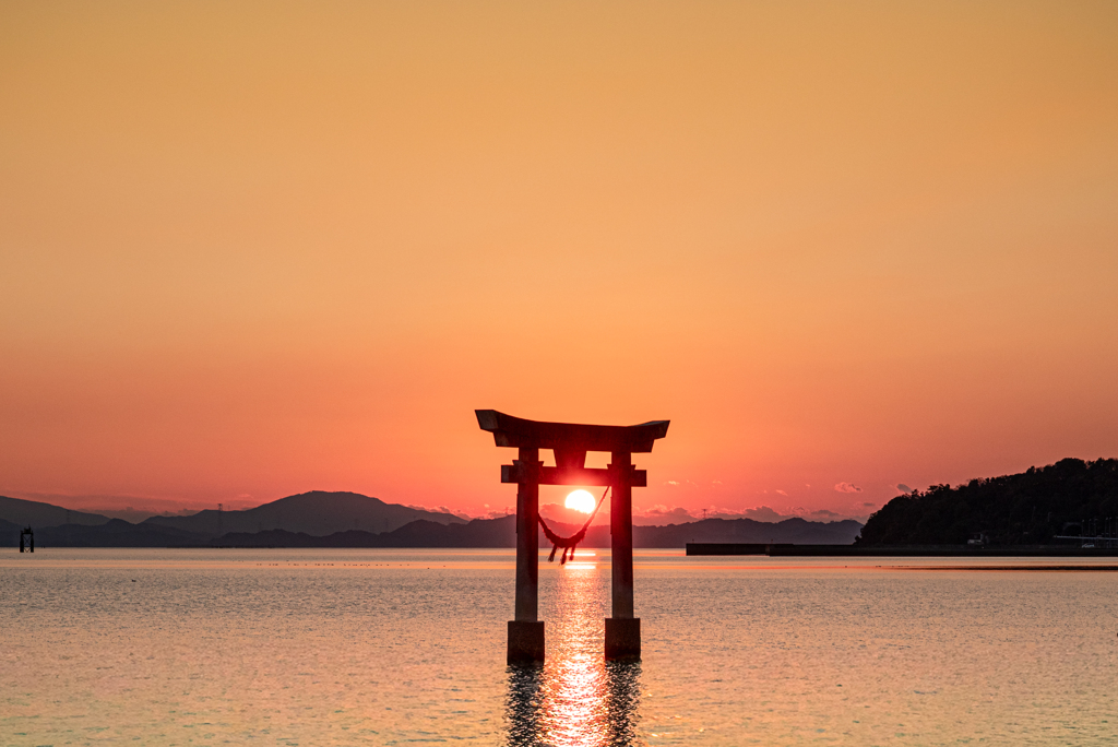 鳥居の中の夕日と光の道