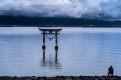 釣り人と鳥居と迫る雲