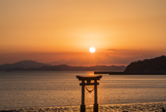 沈み行く夕日と海の鳥居