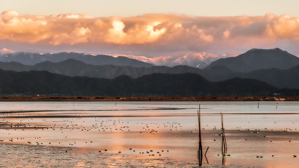 夕日に染まる海と雪山