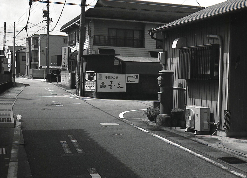 街角の民地に立つ赤ポスト