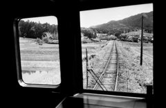 車窓に広がる線路のある里山風景