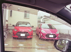 雨の車窓から赤い車が二つ見えた。