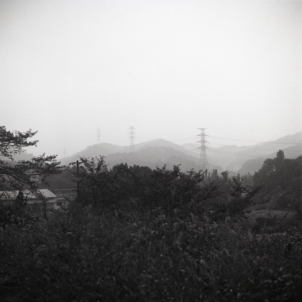 雨に霞む山々の鉄塔群
