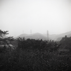 雨に霞む山々の鉄塔群
