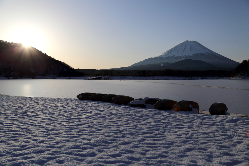 朝日が差す精進湖の雪の浜