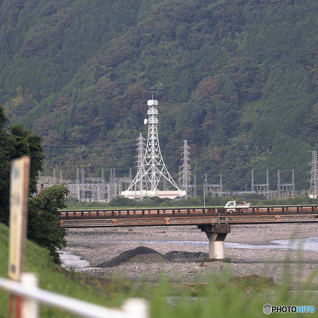 変電所と橋を渡る軽トラ