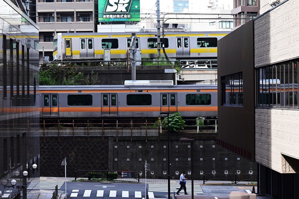 黄色とオレンジの電車と歩く人