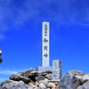 山頂の三角点を通過する登山者