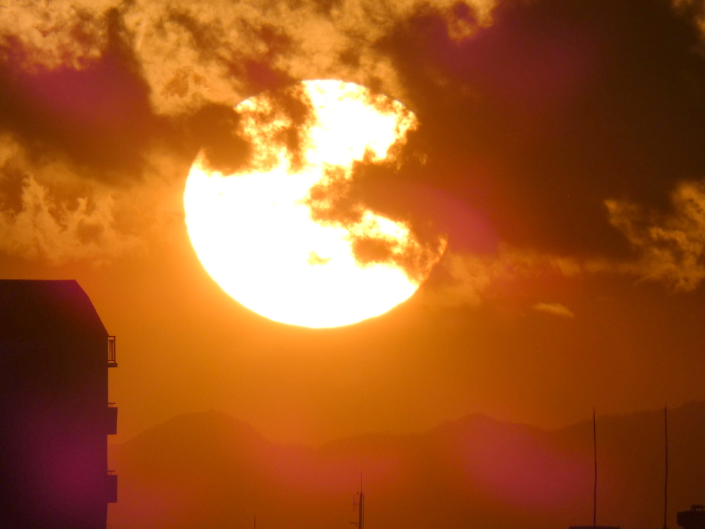 荒川土手から丹沢山系の上空の雲被る大きな夕日