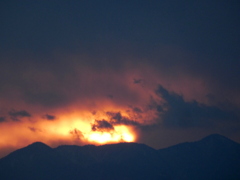 '22.01.13丹沢山系の塔ノ岳と蛭ヶ岳の真ん中の荒れ雲に覆い隠される弱い夕日