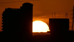 ビルの間の大蔵高丸の上の夕日