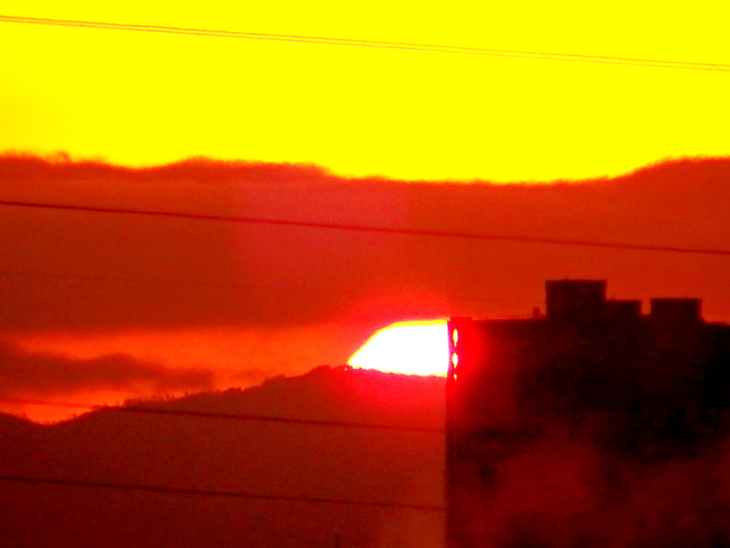 荒川土手から見えた雲間の夕日が丹沢山系の山に