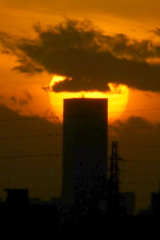 タワービルの後ろの雲被る夕日