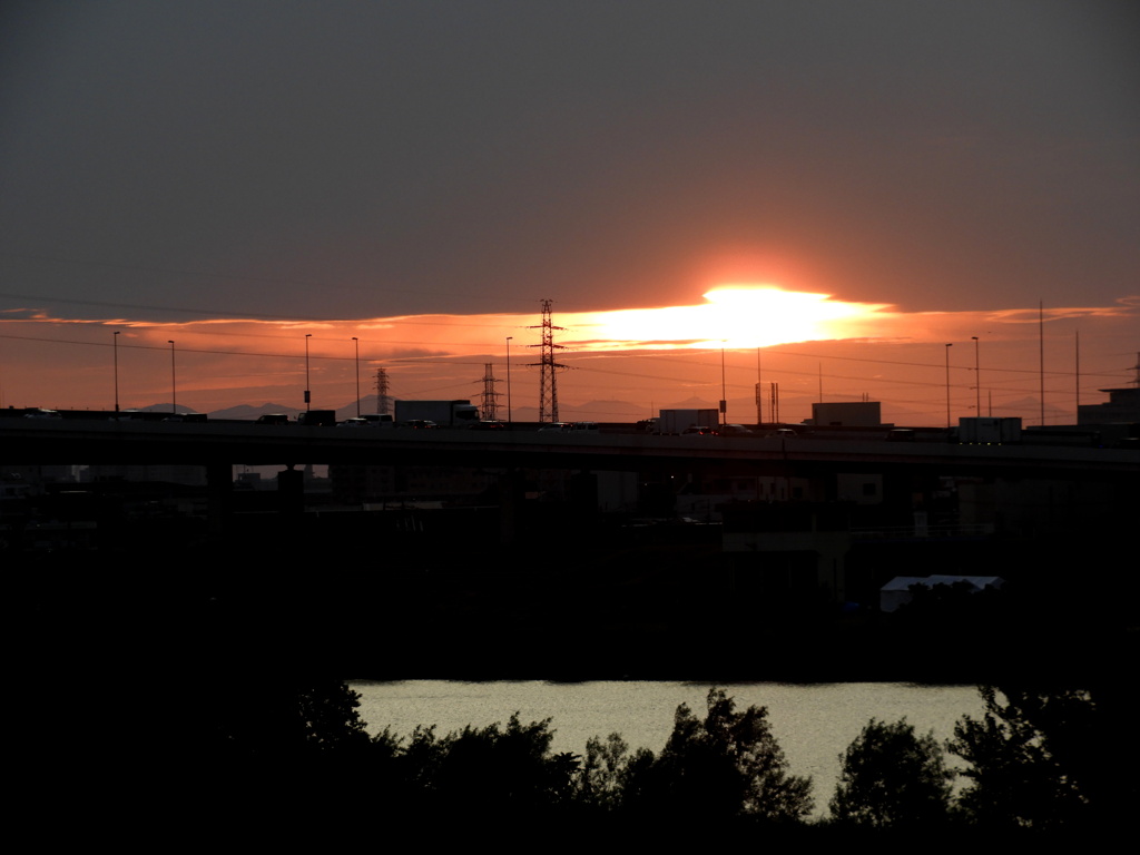 千住新橋から雲間から降りる夕日と高速道路の上に並ぶ秩父の山々