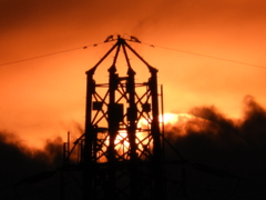 荒川土手から鉄塔の下の黒雲の中に沈む大きな夕日