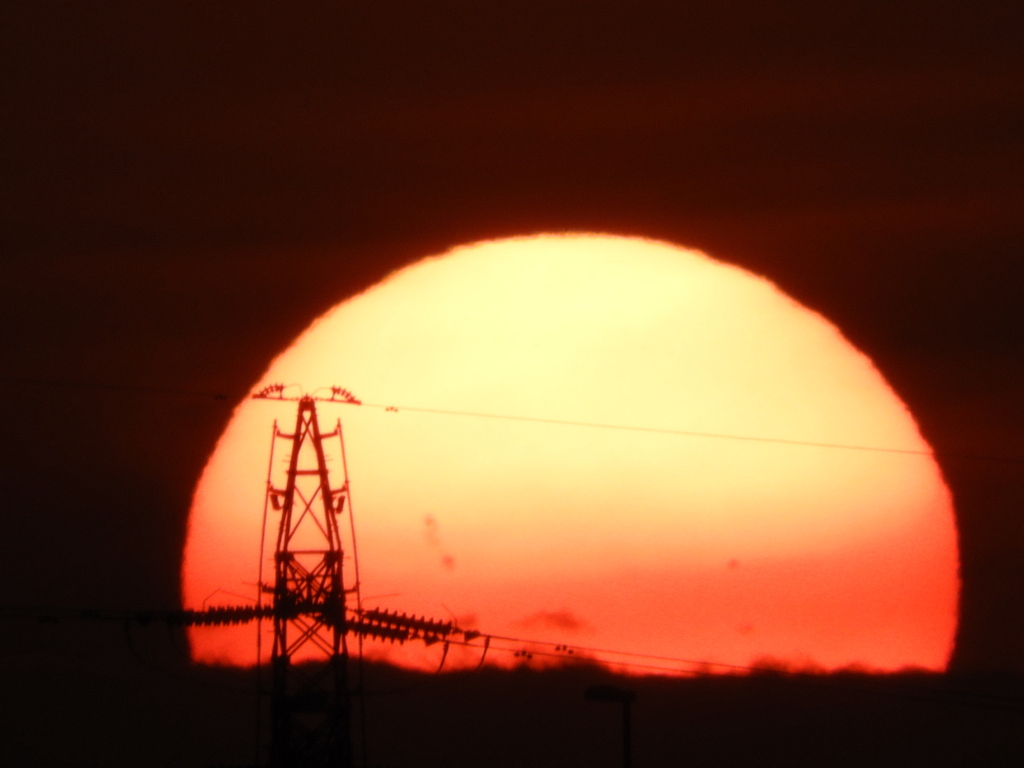 千住新橋から鉄塔の後ろの大きな雲の中に入る大きな夕日