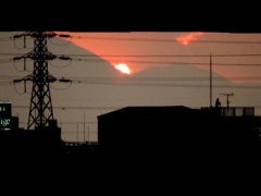 高速下の鉄塔の後ろの笠山(比企郡)の右に出る雲間から降りた夕日の閃光
