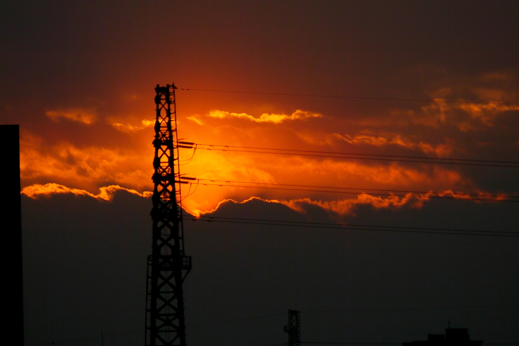 雲に夕日が沈むと鉄塔のうしろは真っ赤な夕焼けが