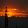 雲に夕日が沈むと鉄塔のうしろは真っ赤な夕焼けが