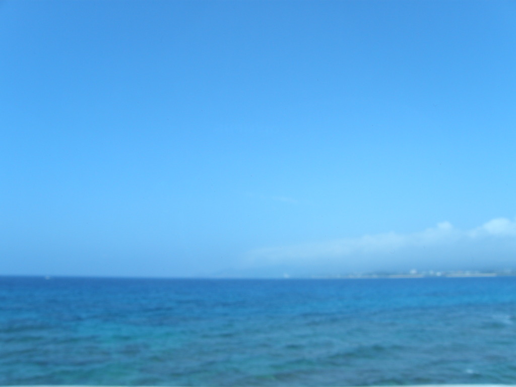 バスの車窓からのマリンブルーの沖縄の海と雲